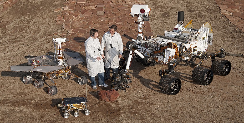 1024px-PIA15279_3rovers-stand_D2011_1215_D521.jpg