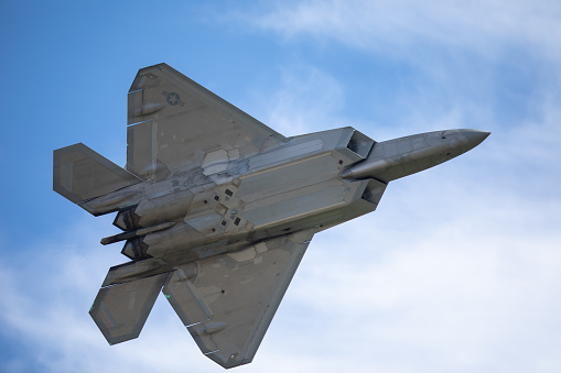 very-close-bottom-view-of-a-f22-raptor-against-clouds-picture-id1147675922