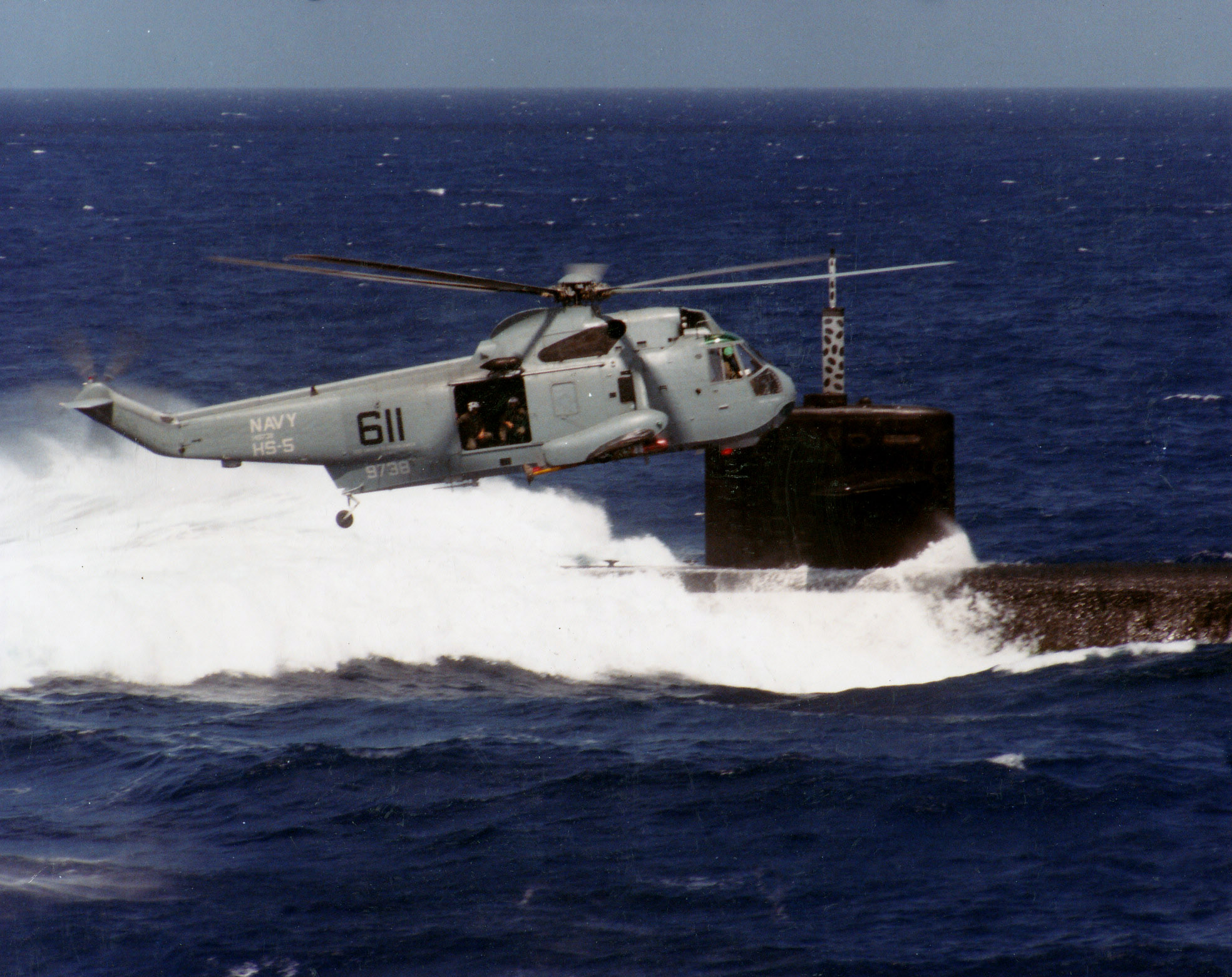SH-3H_Sea_King_of_HS-5_in_flight_over_a_Los_Angeles-class_submarine%2C_circa_1985_%28NNAM.2011.113.393%29.jpg